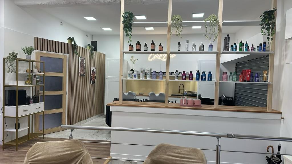 Salon de coiffure rénové avec verrière bois, crédence dorée et sol marbre