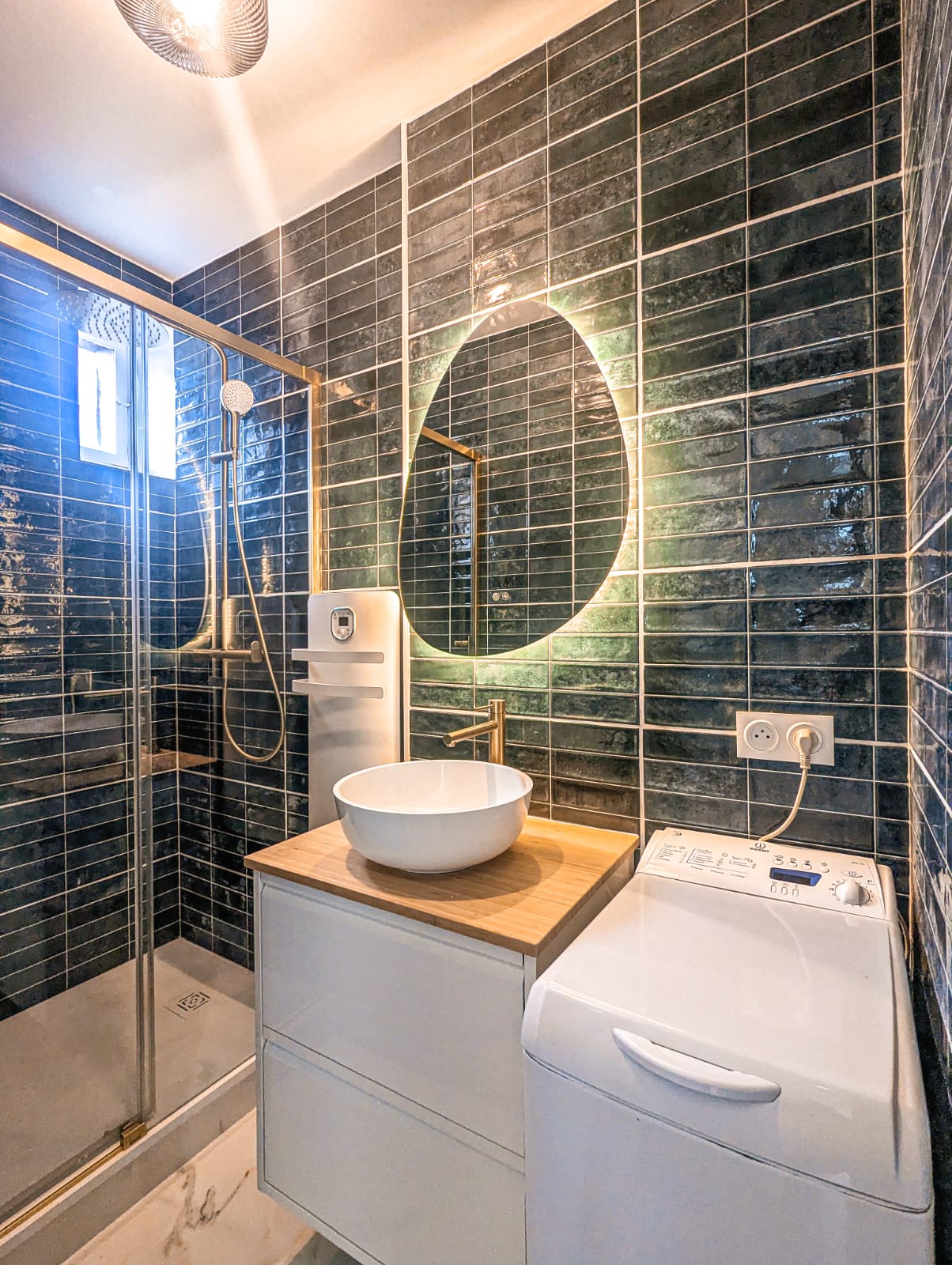 Salle de bain rénovée : faïence vert émeraude, vasque sur meuble bois et robinetterie dorée