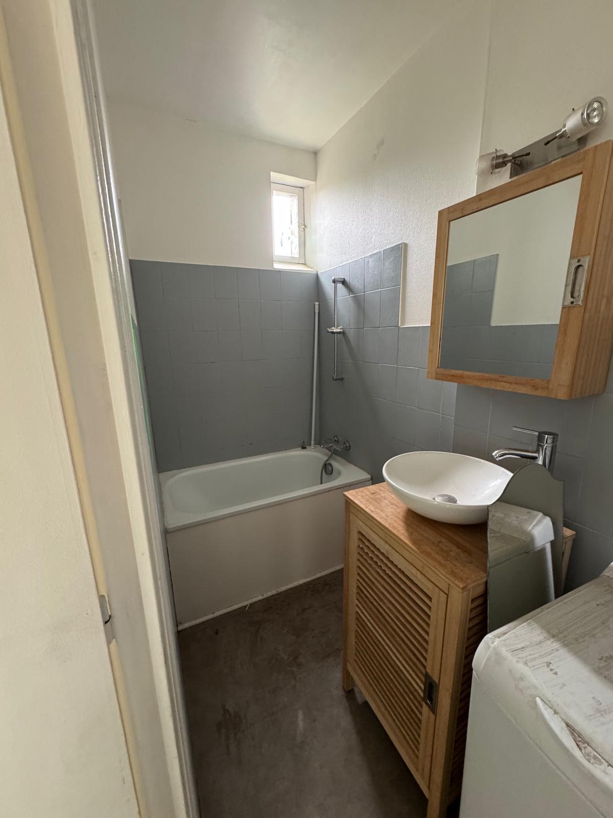 Salle de bain vétuste avec baignoire et faïence bleu-gris avant rénovation