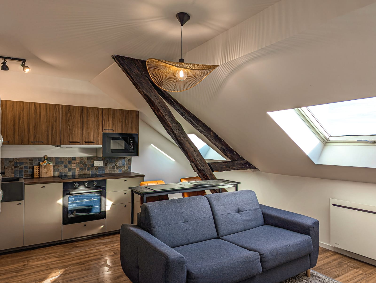 Studio mansardé rénové avec poutres apparentes, cuisine et parquet